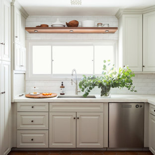 This is an example of a mediterranean kitchen in Los Angeles with beige cabinets, white splashback, stainless steel appliances, terra-cotta floors, an undermount sink, raised-panel cabinets, subway tile splashback, orange floor and white benchtop.
