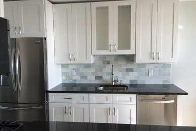 Inspiration for a small contemporary galley porcelain tile eat-in kitchen remodel in New York with an undermount sink, shaker cabinets, white cabinets, granite countertops, blue backsplash, stone tile backsplash, stainless steel appliances and no island