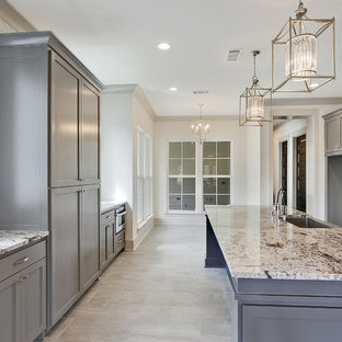 Large traditional galley eat-in kitchen in New Orleans with a farmhouse sink, shaker cabinets, grey cabinets, granite benchtops, white splashback, mosaic tile splashback, stainless steel appliances, ceramic floors and with island.