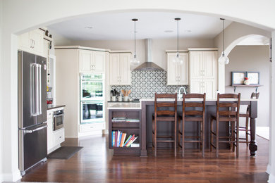 Enclosed kitchen - mid-sized transitional l-shaped dark wood floor and brown floor enclosed kitchen idea in Other with raised-panel cabinets, beige cabinets, multicolored backsplash, stainless steel appliances, an island, an undermount sink, solid surface countertops and cement tile backsplash