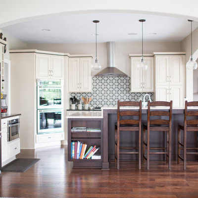 Enclosed kitchen - mid-sized transitional l-shaped dark wood floor and brown floor enclosed kitchen idea in Other with raised-panel cabinets, beige cabinets, multicolored backsplash, stainless steel appliances, an island, an undermount sink, solid surface countertops and cement tile backsplash