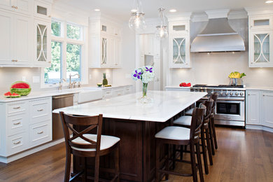 Eat-in kitchen - transitional l-shaped medium tone wood floor eat-in kitchen idea in New York with a farmhouse sink, shaker cabinets, white cabinets, marble countertops, white backsplash, subway tile backsplash, stainless steel appliances and an island