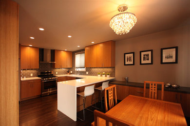 Example of a trendy u-shaped eat-in kitchen design in San Francisco with an undermount sink, flat-panel cabinets, medium tone wood cabinets, quartz countertops, gray backsplash, subway tile backsplash and stainless steel appliances