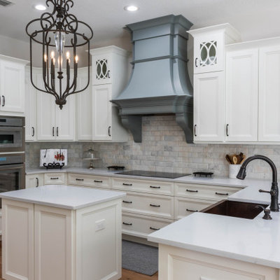 Mid-sized elegant u-shaped medium tone wood floor and brown floor open concept kitchen photo in Orlando with a farmhouse sink, recessed-panel cabinets, white cabinets, quartz countertops, gray backsplash, subway tile backsplash, stainless steel appliances, an island and white countertops