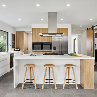 Photo of a scandinavian l-shaped kitchen in Other with an undermount sink, flat-panel cabinets, light wood cabinets, stainless steel appliances, with island, grey floor and white benchtop.