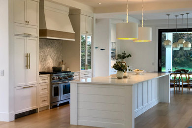 Large transitional single-wall eat-in kitchen photo in Vancouver with a farmhouse sink, shaker cabinets, white cabinets, quartz countertops, gray backsplash, paneled appliances, an island and white countertops