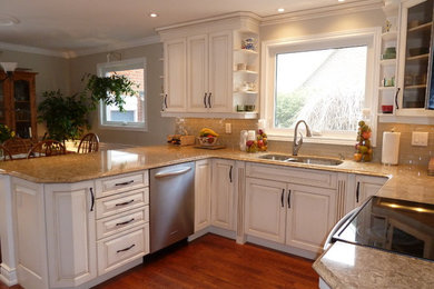 Eat-in kitchen - mid-sized traditional u-shaped medium tone wood floor and brown floor eat-in kitchen idea in Toronto with a double-bowl sink, raised-panel cabinets, white cabinets, beige backsplash, stainless steel appliances, no island, granite countertops, glass tile backsplash and brown countertops