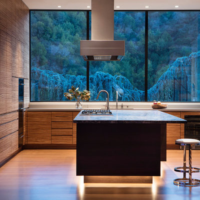 Open concept kitchen - mid-sized contemporary l-shaped medium tone wood floor and brown floor open concept kitchen idea in San Francisco with a single-bowl sink, flat-panel cabinets, medium tone wood cabinets, quartz countertops, gray backsplash, stone slab backsplash, paneled appliances, an island and gray countertops