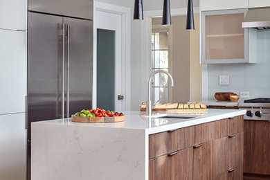 This is an example of a medium sized modern l-shaped kitchen/diner in San Francisco with a built-in sink, glass-front cabinets, dark wood cabinets, engineered stone countertops, green splashback, glass tiled splashback, stainless steel appliances, light hardwood flooring, an island, grey floors and white worktops.