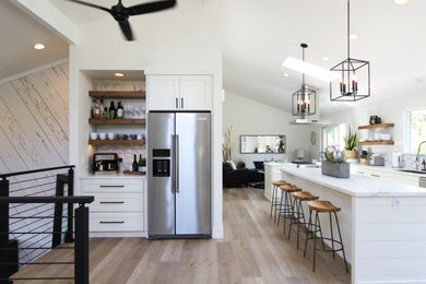 Mid-sized transitional l-shaped vinyl floor, brown floor and vaulted ceiling eat-in kitchen photo in Other with an undermount sink, shaker cabinets, white cabinets, quartz countertops, multicolored backsplash, mosaic tile backsplash, stainless steel appliances, an island and white countertops