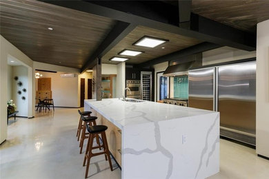 Example of a large minimalist galley limestone floor kitchen design in Los Angeles with a drop-in sink, flat-panel cabinets, black cabinets, marble countertops, ceramic backsplash, stainless steel appliances and an island