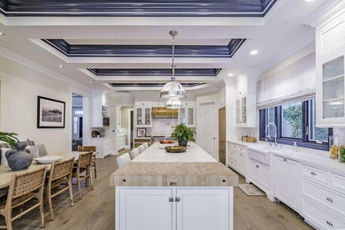 Inspiration for a huge timeless l-shaped medium tone wood floor and brown floor eat-in kitchen remodel in Los Angeles with a farmhouse sink, shaker cabinets, white cabinets, quartzite countertops, white backsplash, subway tile backsplash, paneled appliances, an island and white countertops