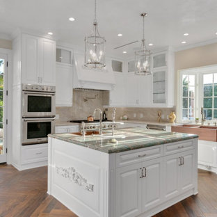 This is an example of a large transitional u-shaped separate kitchen in Los Angeles with a farmhouse sink, shaker cabinets, white cabinets, marble benchtops, beige splashback, marble splashback, stainless steel appliances, dark hardwood floors, multiple islands, multi-coloured floor and turquoise benchtop.