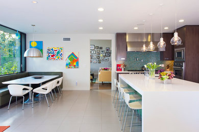 Example of a large trendy single-wall ceramic tile eat-in kitchen design in Los Angeles with a single-bowl sink, flat-panel cabinets, dark wood cabinets, granite countertops, multicolored backsplash, mosaic tile backsplash, stainless steel appliances and an island