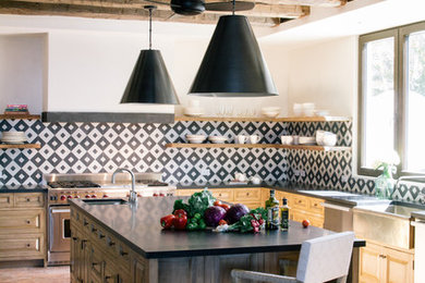 Open concept kitchen - mediterranean l-shaped terra-cotta tile and pink floor open concept kitchen idea in Los Angeles with a farmhouse sink, open cabinets, light wood cabinets, multicolored backsplash, stainless steel appliances and an island