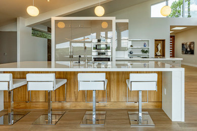 Example of a large trendy galley open concept kitchen design in Austin with flat-panel cabinets, beige cabinets, quartz countertops, white backsplash, two islands and white countertops
