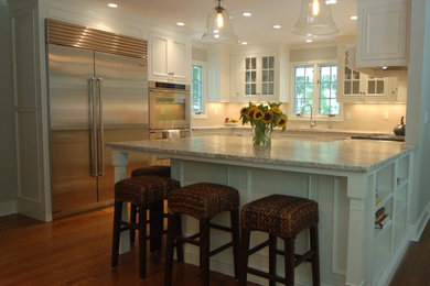 Photo of a large traditional u-shaped kitchen/diner in New York with a submerged sink, beaded cabinets, white cabinets, granite worktops, beige splashback, porcelain splashback, stainless steel appliances, dark hardwood flooring and a breakfast bar.