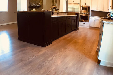 Example of a mid-sized transitional l-shaped medium tone wood floor and brown floor open concept kitchen design in Philadelphia with shaker cabinets, white cabinets, stainless steel appliances and an island