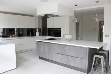This is an example of a medium sized kitchen/diner in Essex with grey splashback, mirror splashback, black appliances and an island.