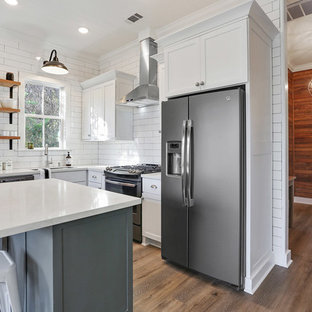This is an example of a small transitional l-shaped eat-in kitchen in New Orleans with an undermount sink, shaker cabinets, white cabinets, quartz benchtops, white splashback, subway tile splashback, stainless steel appliances, vinyl floors and with island.