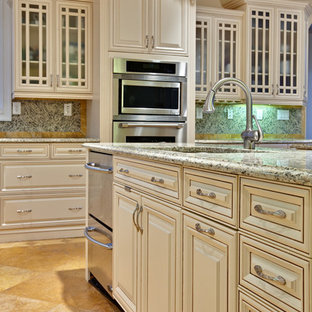 This is an example of an expansive traditional l-shaped eat-in kitchen in Atlanta with raised-panel cabinets, beige cabinets, stainless steel appliances, an undermount sink, granite benchtops, multi-coloured splashback, granite splashback, travertine floors, with island, orange floor and beige benchtop.