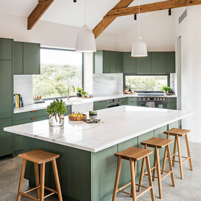 Large trendy l-shaped concrete floor and gray floor open concept kitchen photo in Melbourne with a farmhouse sink, green cabinets, marble countertops, white backsplash, marble backsplash, black appliances, an island, white countertops and flat-panel cabinets