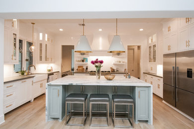 Large transitional u-shaped light wood floor and beige floor open concept kitchen photo in Houston with a farmhouse sink, shaker cabinets, white cabinets, white backsplash, stainless steel appliances, an island and marble countertops