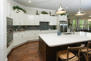 Example of a large classic l-shaped dark wood floor eat-in kitchen design in Atlanta with a single-bowl sink, white cabinets, granite countertops, stainless steel appliances, an island and shaker cabinets