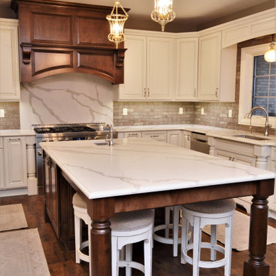 Huge elegant u-shaped medium tone wood floor and brown floor eat-in kitchen photo in Chicago with an undermount sink, raised-panel cabinets, white cabinets, quartzite countertops, gray backsplash, brick backsplash, stainless steel appliances, an island and white countertops