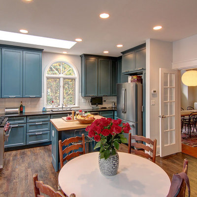 Eclectic u-shaped eat-in kitchen photo in DC Metro with recessed-panel cabinets, blue cabinets, white backsplash, subway tile backsplash and stainless steel appliances