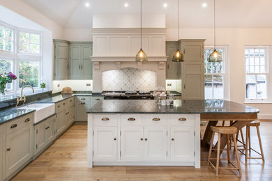 Inspiration for a large traditional l-shaped kitchen/diner in West Midlands with a double-bowl sink, shaker cabinets, green cabinets, granite worktops, integrated appliances, medium hardwood flooring, an island, brown floors and multicoloured worktops.
