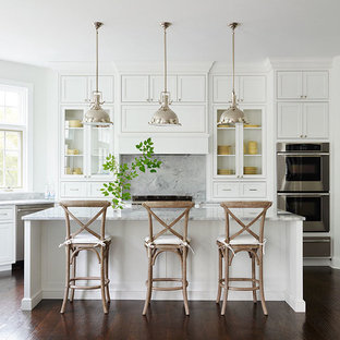 Traditional kitchen ideas - Example of a classic dark wood floor kitchen design in Philadelphia with glass-front cabinets, white cabinets, gray backsplash, stainless steel appliances and an island