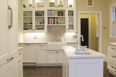 Example of a mid-sized arts and crafts porcelain tile kitchen design in Minneapolis with a farmhouse sink, shaker cabinets, white cabinets, quartzite countertops, gray backsplash and an island
