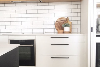Imagen de cocina minimalista con puertas de armario blancas y suelo de bambú