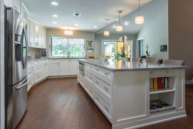 Trendy l-shaped eat-in kitchen photo in Tampa with shaker cabinets, white cabinets, gray backsplash, subway tile backsplash, stainless steel appliances and an island