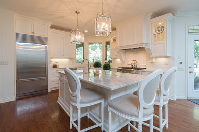 Eat-in kitchen - large transitional l-shaped medium tone wood floor and brown floor eat-in kitchen idea in Detroit with a farmhouse sink, recessed-panel cabinets, beige cabinets, quartzite countertops, beige backsplash, porcelain backsplash, stainless steel appliances and an island