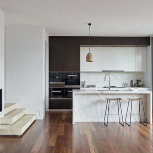 Photo of a mid-sized contemporary galley kitchen in Melbourne with an undermount sink, marble benchtops, white splashback, marble splashback, black appliances, medium hardwood floors, brown floor, white benchtop, flat-panel cabinets, dark wood cabinets and with island.