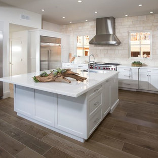 Esempio di una cucina stile marino di medie dimensioni con lavello sottopiano, ante in stile shaker, ante bianche, top in marmo, paraspruzzi beige, paraspruzzi con piastrelle in pietra, elettrodomestici in acciaio inossidabile, parquet scuro, isola e pavimento marrone