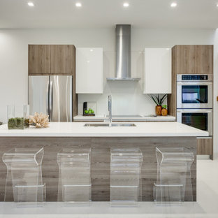 Contemporary kitchen inspiration - Kitchen - contemporary galley gray floor kitchen idea in Miami with an undermount sink, flat-panel cabinets, medium tone wood cabinets, stainless steel appliances, an island and white countertops