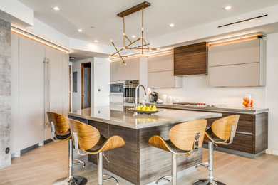 This is an example of a large contemporary open plan kitchen in Los Angeles with a submerged sink, flat-panel cabinets, brown cabinets, engineered stone countertops, white splashback, stone slab splashback, integrated appliances, porcelain flooring, an island and grey worktops.