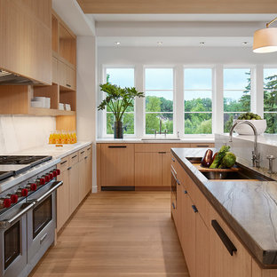 Immagine di una cucina contemporanea con lavello sottopiano, ante lisce, ante in legno chiaro, paraspruzzi bianco, elettrodomestici in acciaio inossidabile, parquet chiaro, top in marmo, paraspruzzi in marmo e 2 o più isole