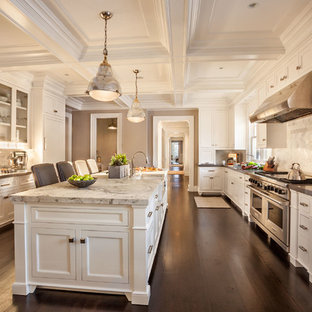 Large traditional enclosed kitchen ideas - Enclosed kitchen - large traditional galley dark wood floor enclosed kitchen idea in New York with a farmhouse sink, shaker cabinets, white cabinets, marble countertops, white backsplash, stone tile backsplash, stainless steel appliances and an island