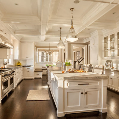 Large transitional u-shaped dark wood floor kitchen photo in New York with a farmhouse sink, shaker cabinets, white cabinets, marble countertops, white backsplash, porcelain backsplash, stainless steel appliances and an island