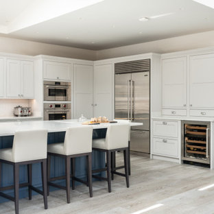 Inspiration for a classic l-shaped kitchen in London with beaded cabinets, white cabinets, stainless steel appliances, light hardwood flooring, an island, beige floors, white worktops, a drop ceiling and a vaulted ceiling.