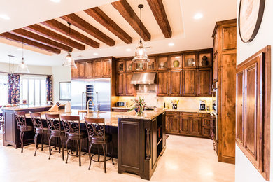 Inspiration for a large country l-shaped travertine floor open concept kitchen remodel in Austin with a single-bowl sink, raised-panel cabinets, medium tone wood cabinets, granite countertops, beige backsplash, stone tile backsplash, stainless steel appliances and an island