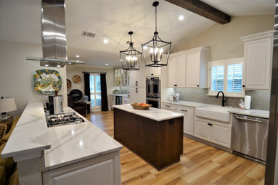 ヒューストンにあるトランジショナルスタイルのおしゃれなアイランドキッチン (エプロンフロントシンク、ガラスタイルのキッチンパネル、磁器タイルの床、茶色い床) の写真