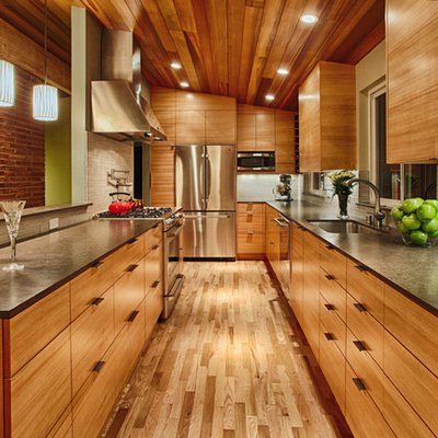Mid-sized trendy galley medium tone wood floor and brown floor open concept kitchen photo in Seattle with flat-panel cabinets, medium tone wood cabinets, gray backsplash, stainless steel appliances, an undermount sink, quartz countertops and porcelain backsplash
