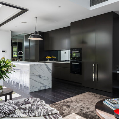 Inspiration for a mid-sized contemporary galley dark wood floor and brown floor open concept kitchen remodel in Sydney with an undermount sink, marble countertops, mirror backsplash, black appliances, an island, white countertops, flat-panel cabinets and black cabinets