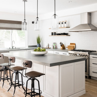 Kitchen - cottage medium tone wood floor and brown floor kitchen idea in Orange County with an undermount sink, shaker cabinets, white cabinets, white backsplash, subway tile backsplash, stainless steel appliances, an island and gray countertops