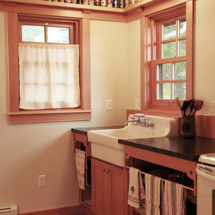Photo of a small traditional single-wall open plan kitchen in Portland with a farmhouse sink, open cabinets, medium wood cabinets, solid surface benchtops, brown splashback, white appliances, bamboo floors, no island and brown floor.